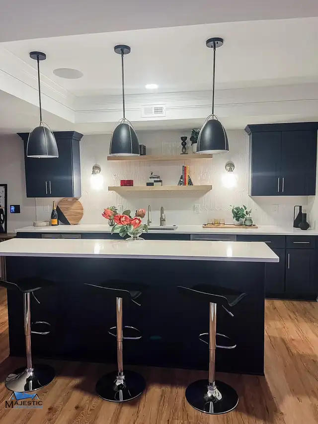 Basement kitchenette in Shelby Township with black cabinets, a white island, floating wood shelves and black dome pendants