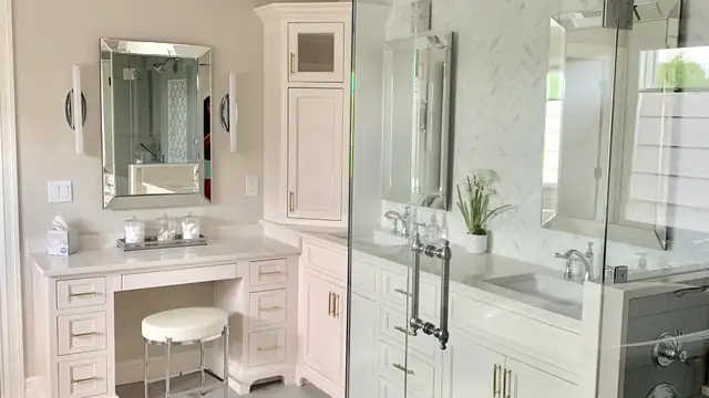 Remodeled bathroom with a white makeup vanity, sink cabinet with tall linen tower and a glass-enclosed shower