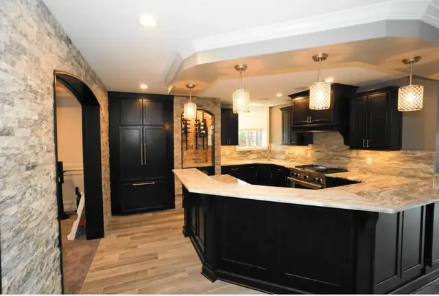 Rochester Hills basement bar with dark cabinets, a stone-look counter, stacked stone wall and pendant lights