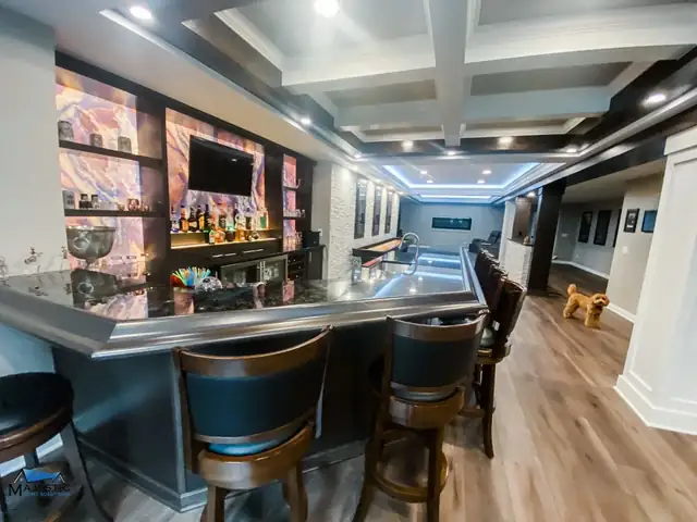 Shelby Township basement bar with a coffered ceiling, backlit shelving and leather-back bar stools