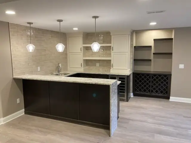 Finished basement wet bar in Novi, MI with dark cabinets, pendant lights, open shelving and a built-in wine rack